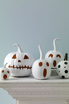 white pumpkins decorated with polka dots and jack - o - lantern faces on a mantle