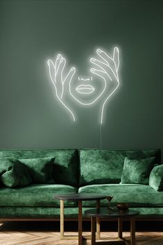 a living room with a green couch and a neon light drawing on the wall above it