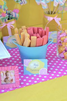 there is a blue bucket full of candy and candies on the table in front of it