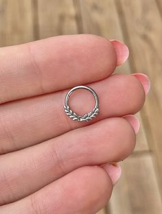 a woman's hand holding a silver ring with leaves on the inside of it