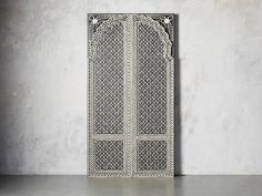 an intricately designed door is shown against a white wall and concrete floor with no one in it