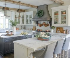 a large kitchen with white cabinets and marble counter tops, an island in the middle