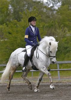 a woman riding on the back of a white horse