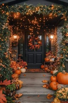 a porch decorated for fall with pumpkins and greenery on the steps, lights strung over the front door