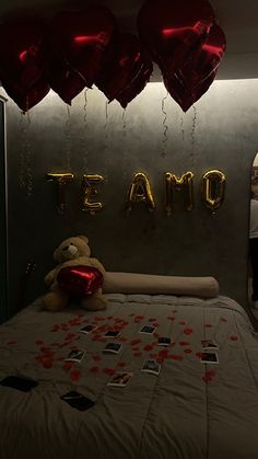 a teddy bear sitting on top of a bed in a room with balloons and confetti