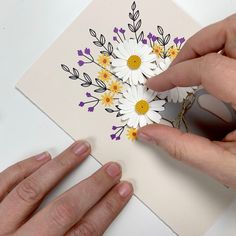 someone is cutting out some flowers on a piece of paper