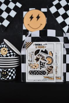 a black and white checkered table cloth with cupcakes, plates and napkins