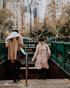 two women in coats are walking up the stairs