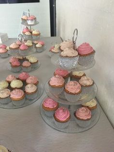 cupcakes are arranged on top of each other in glass trays with silver stands