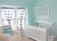 a baby's room decorated in blue and gray with chevrons on the curtains