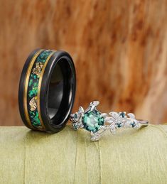 a wedding ring with green and gold flowers on the inside is sitting on top of a cushion