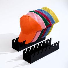 a hat rack with five different colored hats on it and one is upside down in the air