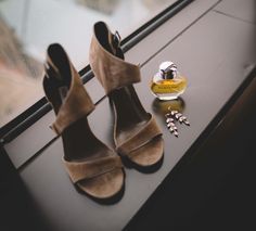 a pair of shoes sitting on top of a window sill next to a bottle of perfume