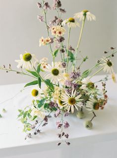 a vase filled with lots of flowers on top of a white countertop next to a wall