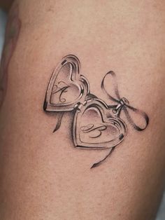 a tattoo with two hearts and a bow on the thigh