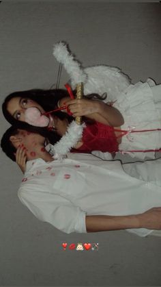 two people dressed up as angels and one is holding a candy cane in her mouth