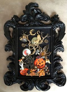 an ornate black frame with halloween decorations and pumpkins on it's sides, hanging from the wall