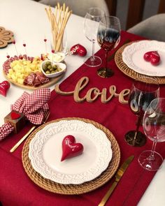 the table is set with plates, silverware and red napkins that spell out love