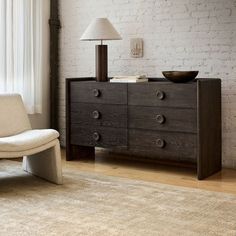 a white chair sitting next to a wooden dresser on top of a hard wood floor