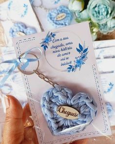 a card with a heart shaped keychain attached to it, in front of some flowers