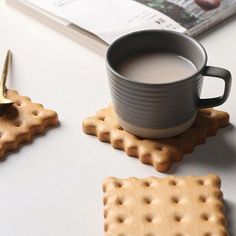 a cup of coffee sitting on top of a table next to crackers and cookies