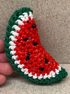 a hand holding a piece of fruit made out of beads