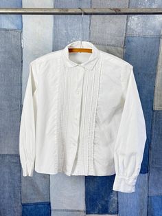 "An authentic vintage womens long sleeve shirt blouse with pleated detail  era : 1950s 60s material : cotton color : white condition : great, appropriate signs of age and wear as seen in photos size : xsmall to small , please compare measurements below actual garment measurements : chest : 39\" shoulder : 14\" sleeve : 21\" length : 21\" - - - - - - - - - - - - - - - - - - - - - - - - - - - - - - - - - - - - - - - -  INTERNATIONAL SHIPPING AVAILABLE UPON REQUEST Craft Union does NOT accept returns or exchanges, all items are FINAL SALE Please consider the following prior to placing an order : Because measurements are provided, Craft Union does NOT grant refund/exchange requests if an item does not fit. We are always happy to assist interest buyers with any size/fit concerns using the \"ask Classic Cotton Tops With Peter Pan Collar, Long Sleeve Cotton Tops With Pintucks, Cotton Long Sleeve Tops With Pintucks, Cotton Long Sleeve Blouse With Pintucks, Cotton Tops With Pintucks For Daywear, Cotton Workwear Tops With Pintucks, Classic Cotton Blouse With Peter Pan Collar, Pintuck Long Sleeve Tops For Daywear, Long Sleeve Tops With Pintucks For Daywear