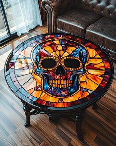 a stained glass table with a colorful skull on it's face in front of a couch