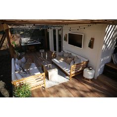 an outdoor living area with couches, table and television on the deck in the back yard