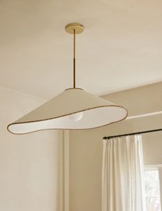 a light fixture hanging from the ceiling in a room with white curtains and drapes