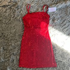 a red dress is laying on top of a gray carpet with a price tag attached to it