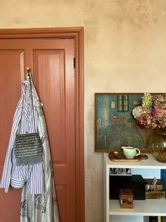 a room with a book shelf, vase and coat rack