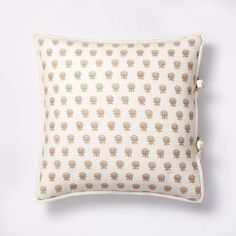 a white pillow with an embroidered design on the front and back, sitting on a white surface