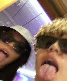 two people with sunglasses and one is sticking out his tongue