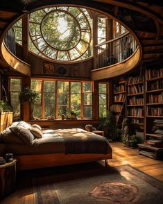 a bed sitting under a large window next to a bookshelf filled with lots of books