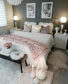 a white bed sitting in a bedroom next to two nightstands with candles on them