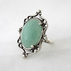 This ring is a sterling silver setting with a 18 mm x 13 mm green Aventurine cabochon set in a beautiful Sterling Silver frame ring and aged to resemble an antiqued heirloom.   Due to the handmade nature of the creation, each piece may have slight variations. All items come with free resize and maintenance for the life of the product. Silver Chrysoprase Cabochon Emerald Ring, Vintage Sterling Silver Oval Emerald Ring, Vintage Oval Emerald Ring In Sterling Silver, Green Cabochon Moonstone Ring In Sterling Silver, Ring My Bell, Frame Ring, Cameo Ring, Cameo Pendant, Eye Pendant