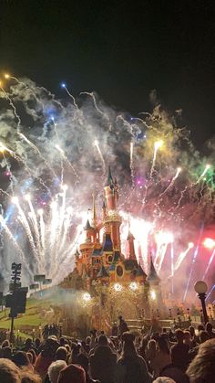 fireworks light up the night sky over a castle at disneyland's new year's eve celebration