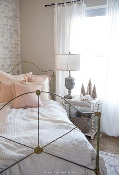 a white bed sitting next to a window in a room with curtains on the windowsill