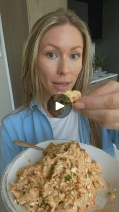 a woman is eating food out of a white bowl with a spoon in her hand