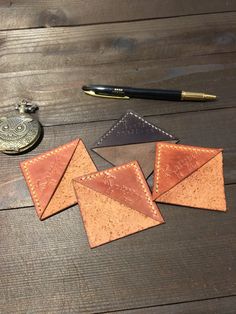 three pieces of leather sitting on top of a wooden table next to a pocket watch