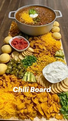 a platter filled with chips and dips next to a pot of chili cheese