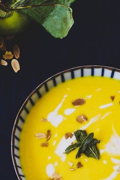 a bowl filled with yellow soup and topped with nuts