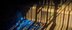 shadows cast on the floor and stairs in front of a window with blue yarn hanging from it