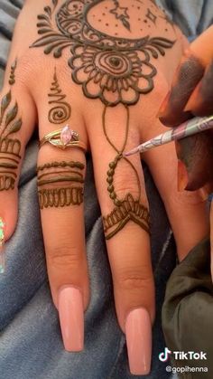 someone is doing henna designs on their hands and fingers with a pen in hand