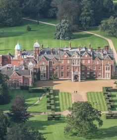 an aerial view of a large brick building in the middle of a lush green field