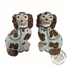 two white and brown dog figurines sitting next to each other on a white background