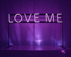 a neon sign that says love me in front of a purple background with the word love me on it