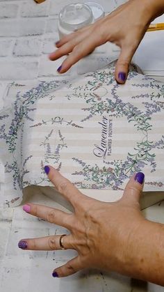 two hands on top of a piece of paper with writing and flowers painted on it