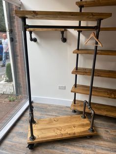 a wooden shelf sitting next to a window in a room with metal pipes on it